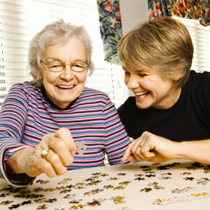 Friendly visitor doing puzzle with senior