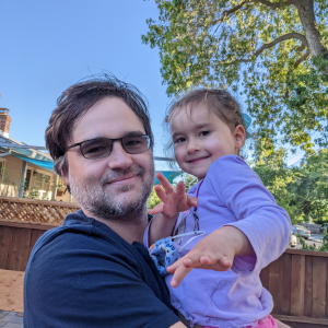 A man poses with his small child in his arm. 