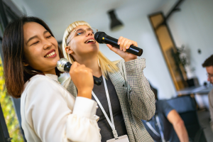 two women sing karaoke while smiling