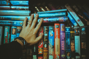 A hand sorting through a stack of VHS tapes