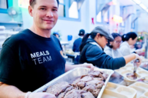 A teen holds a tray of food in a free meal kitchen for the homeless