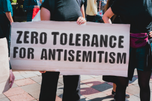 teenager holding up a sign that reads zero tolerance for antisemitism