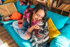 Woman drinking tea, cuddling with dog