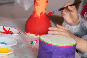 A child's hand painting a flower pot