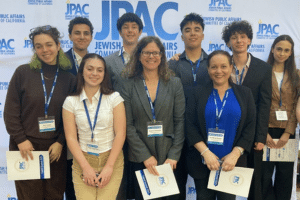 A group of teens mental health advocates pose in front of a JPAC banner